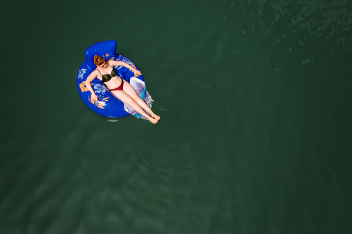 Woman floating on the river on inflatable ring in bikini, directly above