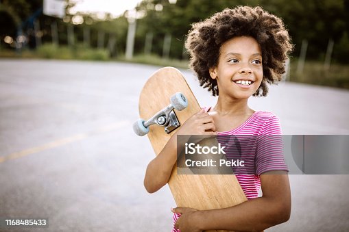 istock Cheerful African girl holding skateboard 1168485433