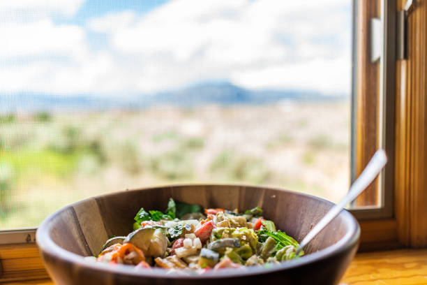 крупным планом свежего зеленого салата в деревянной тарелке чаши подоконником в таосе с видом на гору в пустынном районе нью-мексико со сме - ranchos de taos стоковые фото и изображения