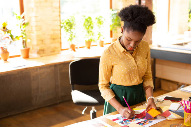 istock Stylish curly designer holding pencil while working hard 1168517357