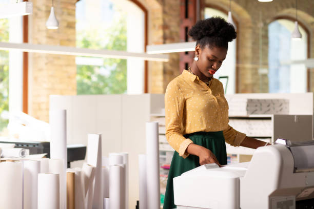 istock Young dark-haired worker with curly hair standing near printer 1168517406