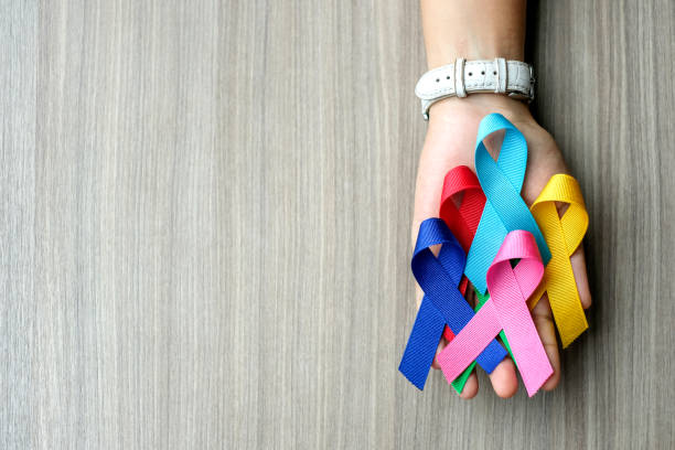 всемирный день рака (4 февраля). красочные ленты осведомленности; синий, красный, зеленый, розовый и желтый цвет на деревянном фоне для подде� - раковая опухоль стоковые фото и изображения