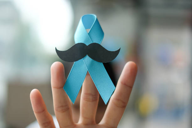 consapevolezza del cancro alla prostata, ha vinto una mano tenendo il nastro blu chiaro con baffi per sostenere le persone che vivono e malattie. men healthcare e world cancer day concept - mustache ethnic asian ethnicity men foto e immagini stock