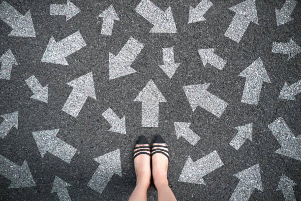 pies y flechas en el fondo de la carretera. mujer de pie con muchas opciones de flecha de signo de dirección de diferentes maneras, izquierda y adelante. - new possibilities fotos fotografías e imágenes de stock