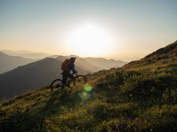 Mountain biker pushing his bicycle to the mountain peak.
