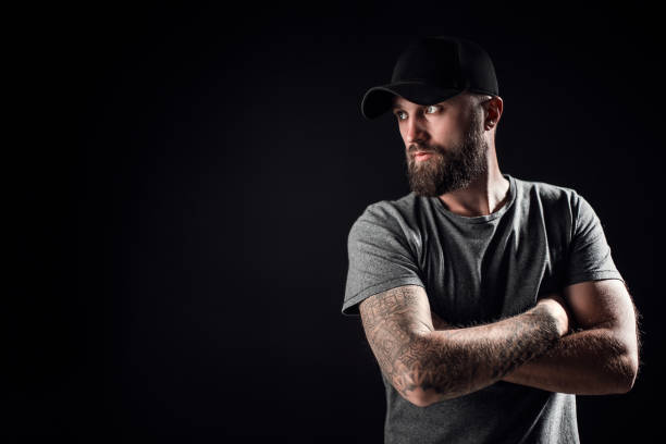 pensive negro barbudo macho vestido con una camisa gris, gafas de sol y gorra de béisbol - attractive male men baseball cap male fotografías e imágenes de stock