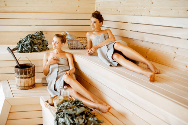 petites amies détendant dans le sauna - sauna health spa healthy lifestyle wellbeing photos et images de collection
