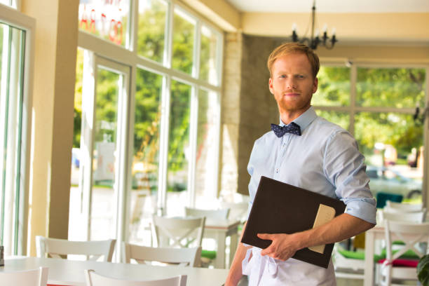 istock Portrait of confident young waiter holding menu while standing at restaurant 1168537013
