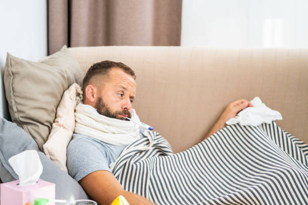 istock High temperature concept. Man feels badly ill. How to bring fever down. Cold symptoms and causes. Sick man with flu. Man hold thermometer. Measure temperature. Break fever remedies. 1168539165
