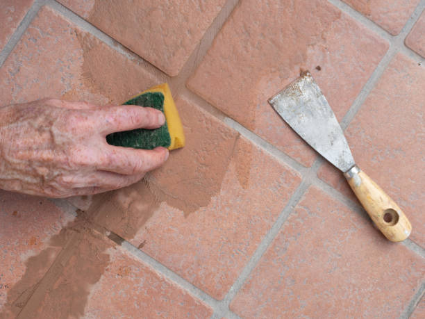 istock Unidentified man, workman, sponging down repaired grout between outdoor terracotta style patio tiles. Closeup detail. 1168542849