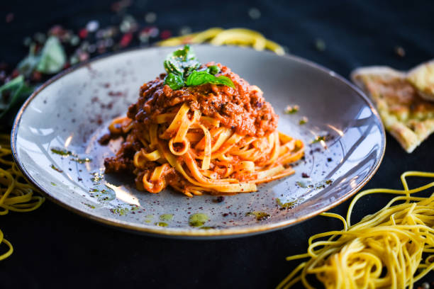 deliziosi spaghetti alla bolognese italiani con salsa di manzo tritato, pomodori, carote e basilico fresco - ragù foto e immagini stock