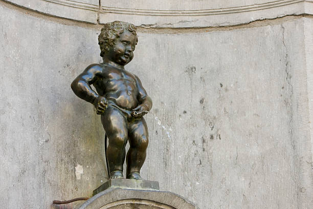 Mannekin Pis in Brussels Belgium with a full stream spraying forth as he wears a military uniform