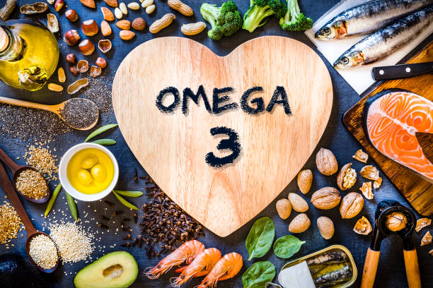 Assortment of food rich in omega-3 Top view of wooden cutting board with a heart shape surrounded by an assortment of food rich in Omega-3 like various kinds of nuts like hazelnuts, peanuts and almonds, canned and raw fish like salmon and sardine, some heaps of seeds like chia seeds, quinoa and flax seeds, some fruits like avocado and olives, vegetables like spinach and broccoli, and olive oil. The cutting board has a "Omega 3" text written on top.
Low key DSLR photo taken with Canon EOS 6D Mark II and Canon EF 24-105 mm f/4L Omega-3 Fatty Acids stock pictures, royalty-free photos & images