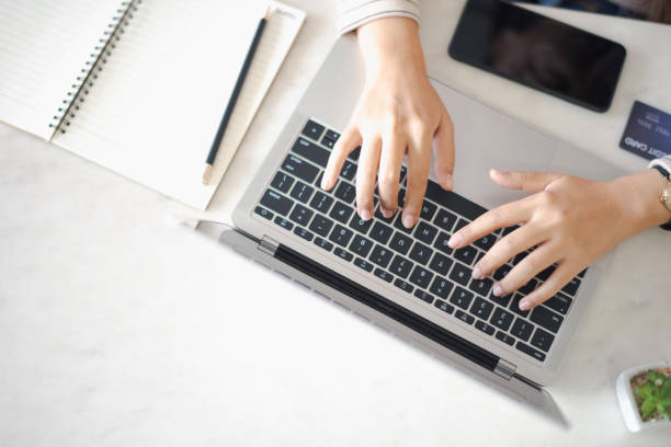 istock Closed up and focus on hand of young woman using a notebook laptop which put on white table and have smartphone, credit card note book put in near. see from top view. co working space concept. 1168546273