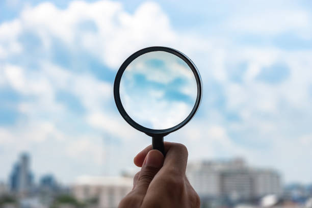 istock hands holding glass magnify against blue sky background. Business Explore, Searching, Discovery and Vision concepts 1168546604