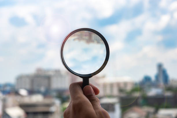 istock hands holding glass magnify against blue sky background. Business Explore, Searching, Discovery and Vision concepts 1168548505
