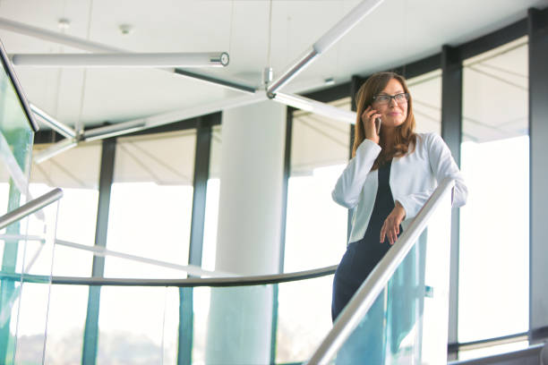 istock Low angle view of businesswoman talking on smartphone while standing at office 1168548913
