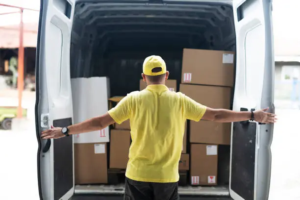 Photo of Man Opens Rear Doors Of Delivery Van