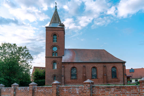 Church in Guelpe, Germany with two storks breeding on the clock tower roof