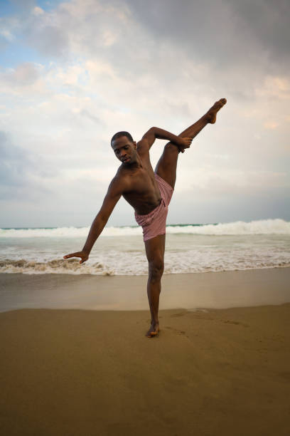 istock dramatic contemporary dance choreographer doing ballet beach workout . young attractive and athletic afro black American man dancing on sunrise doing performance rehearsal 1168550261