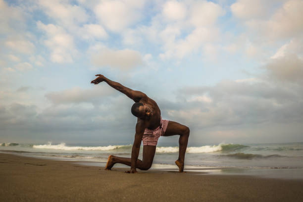 istock dramatic contemporary dance choreographer doing ballet beach workout . young attractive and athletic afro black American man dancing on sunrise doing performance rehearsal 1168550466
