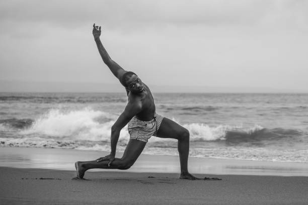 istock dramatic contemporary dance choreographer doing ballet beach workout . young attractive and athletic afro black American man dancing on sunrise doing performance rehearsal 1168551055