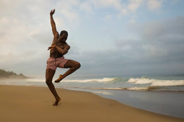 dramatic contemporary dance choreographer doing ballet beach workout . young attractive and athletic afro black American man dancing on sunrise doing performance rehearsal dramatic contemporary dance choreographer doing ballet beach workout . young attractive and athletic afro black American man dancing on sunrise doing performance rehearsal contemporary dance stock pictures, royalty-free photos & images