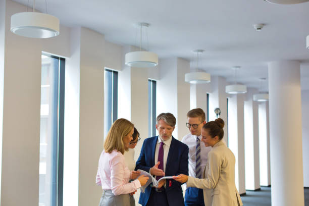 istock Business people discussing over document while standing in corridor at office 1168554235