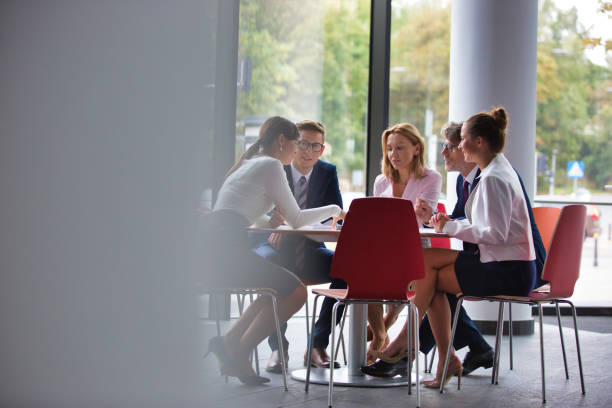 istock Business colleagues discussing while sitting at table in office lobby during meeting 1168556340
