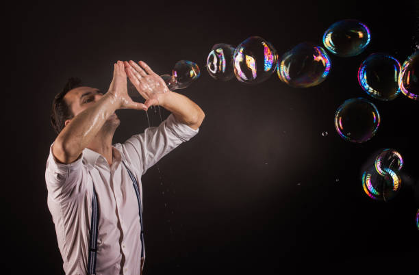 istock Artist blowing many soap bubbles from his hands. Bubble show studio concept. 1168564730