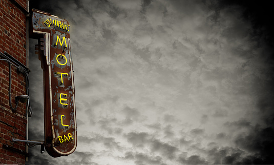 A Grungy Old Neon Motel Sign Against A Stormy Sky With Copy Space