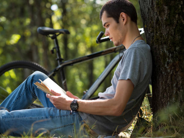 istock Student sitting on the grass in the Park and reading a book 1168570697