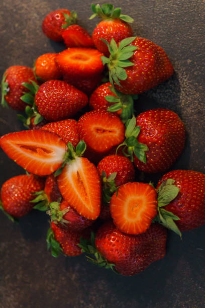 istock Fresh whole and sliced strawberries on a dark table. 1168571782