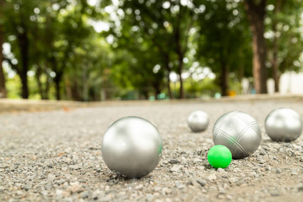 petanque bälle auf dem spielfeld mit schattigen bäumen als kulisse. - pétanque stock-fotos und bilder