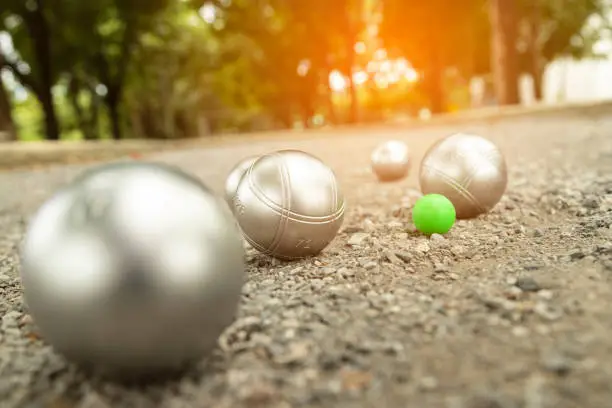 Petanque balls in the playing field with shady trees as a backdrop.