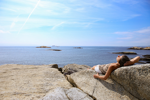 Woman sunbathing on a rock in The End of the Earth in Norway.