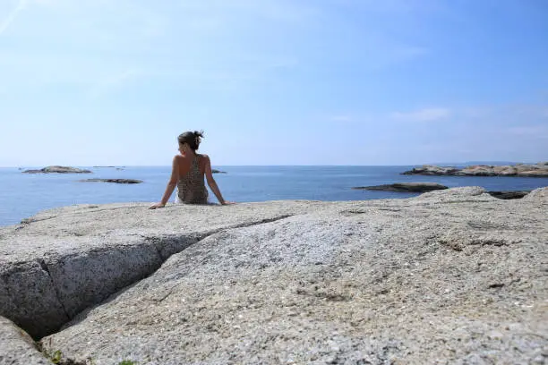 Photo of Woman admiring magestic view  of islets and rocks in The End of the Earth in Norway.