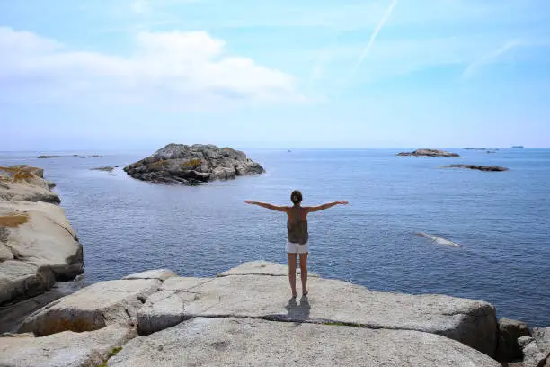 Photo of Woman admiring magestic view  of islets and rocks in The End of the Earth in Norway.