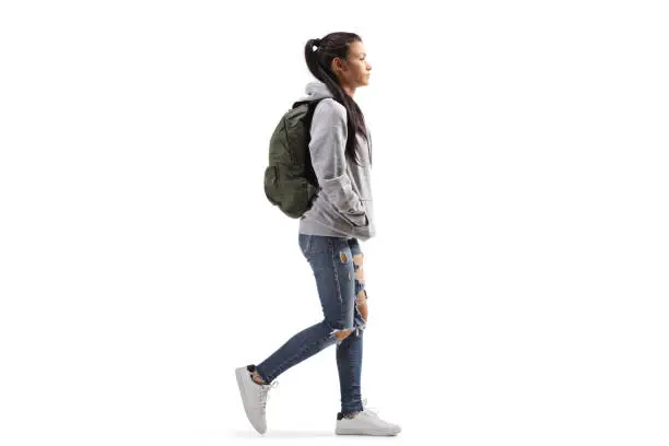 Photo of Female student wearing a hoodie and ripped jeans walking