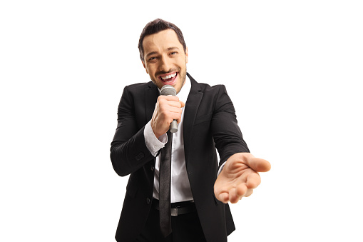 Young man in a suit smiling and holding a microphone isolated on white background