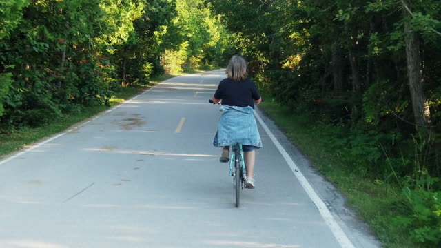 A Video Clip Of A Mature Smiling Woman Riding A Bicycle Enjoying The Scenery