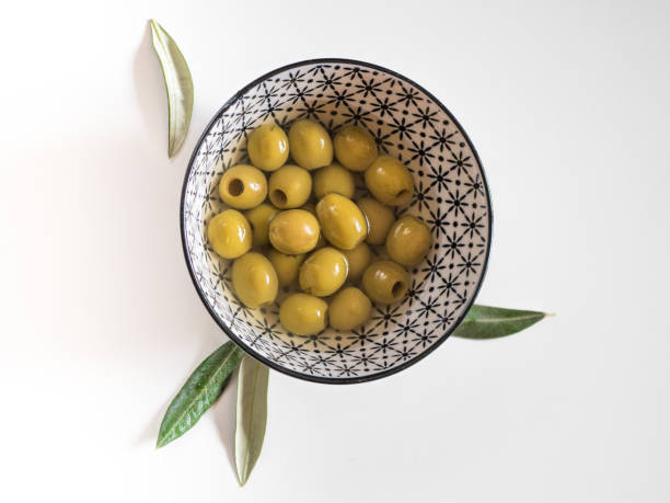 Pitted olives in a bowl on white background