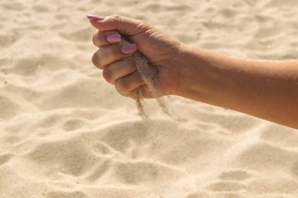 istock The sand is pouring from woman's hands. 1168586684
