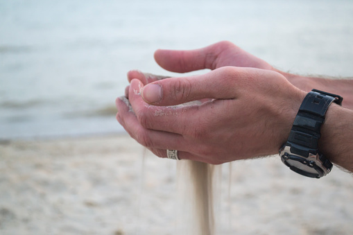 The sand is pouring from male hands.