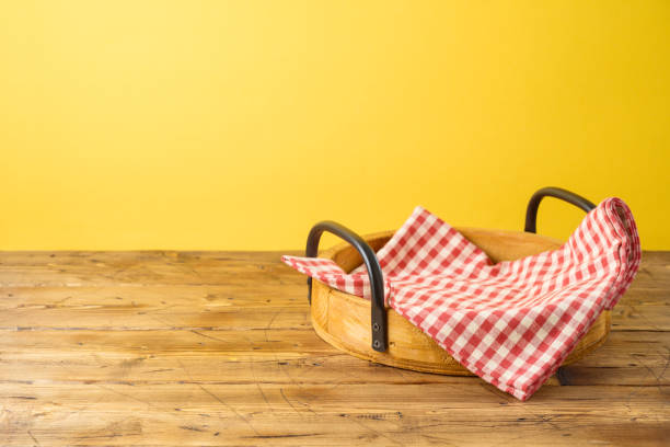 istock Empty wooden tray with red checked tablecloth on wooden table over yellow background 1168587656