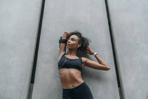 istock Female taking a rest after training session, leaning to a wall and stretching standing outdoors 1168590879