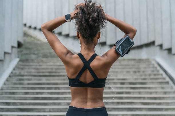 Rear view of woman runner tying her hair and getting ready for another run outdoors Women, One Woman Only, Muscular Build, Young Women, Athlete woman tying hair in ponytail getting ready for exercising stock pictures, royalty-free photos & images