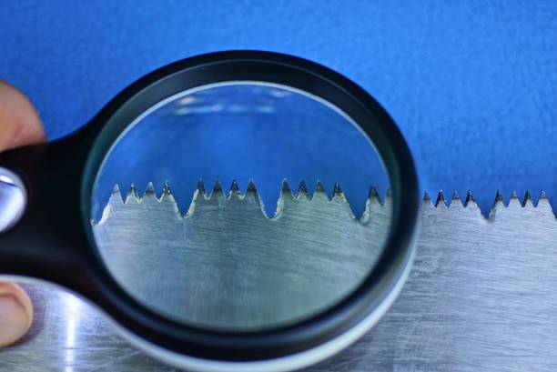 black magnifier increases sharp steel teeth on a gray saw