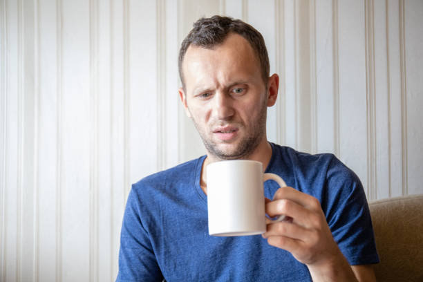 disgusted young man looks in a mug with a drink