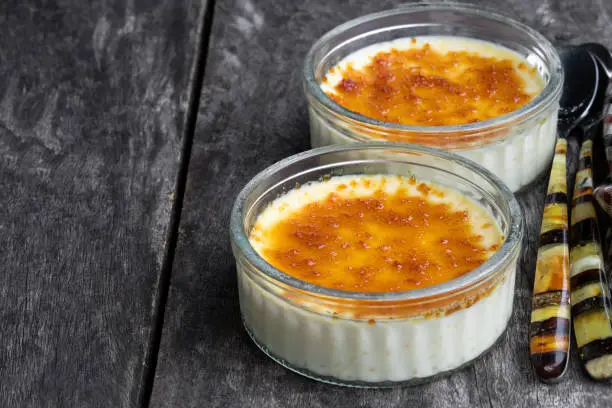 Closeup  of creme brulee in glass jars on rustic wooden table